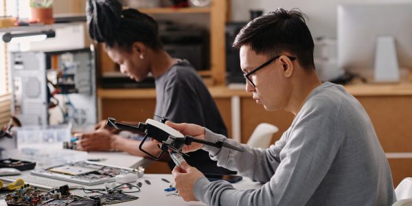 Biracial Colleagues Repairing Electronic Devices in Workshop