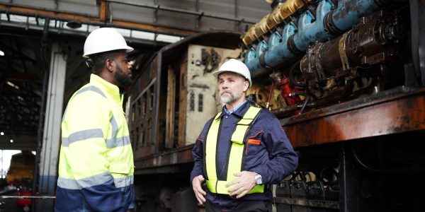 Portrait of engineer and apprentice in workshop of railway engineering facility