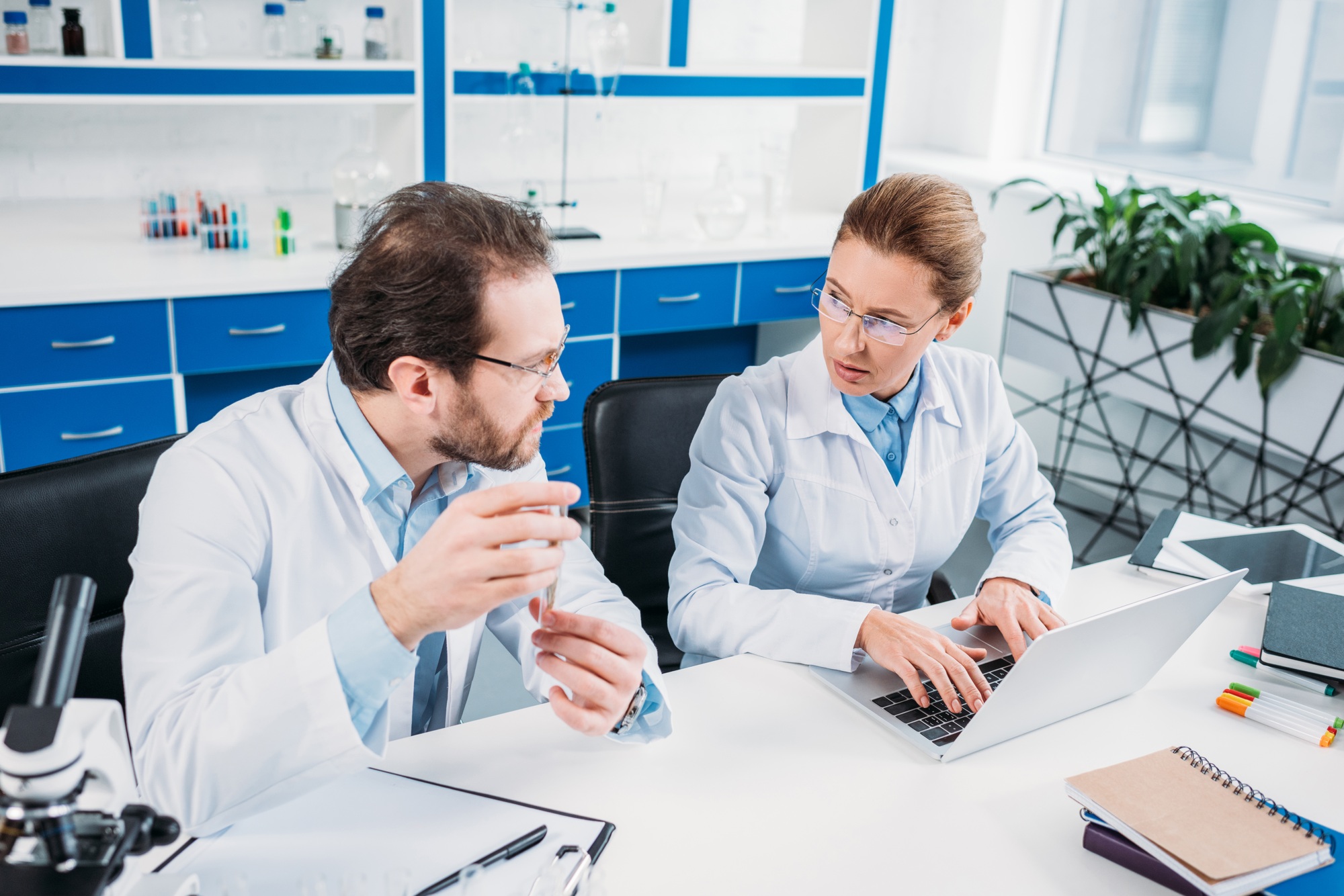 scientific-researchers-in-white-coats-discussing-work-at-workplace-in-laboratory-1.jpg